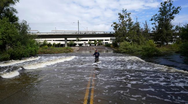 Journaliste de télévision au milieu d'une route inondée